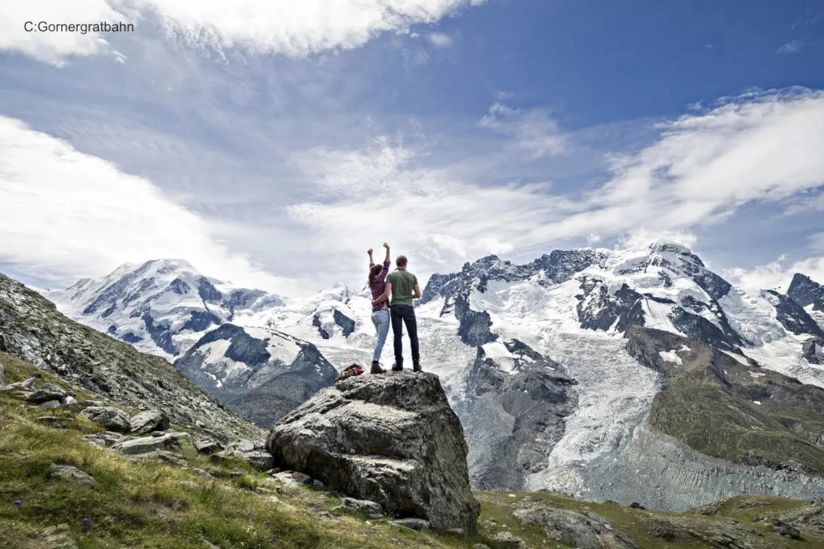 Hikers atop peak with glaciers in the background